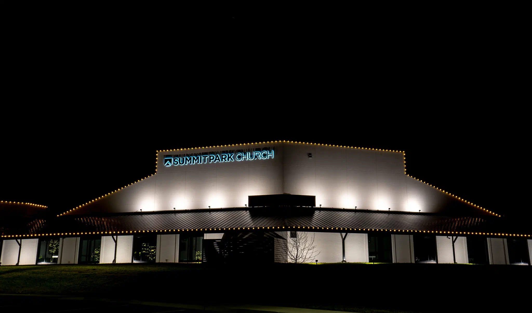 Summit Park Church exterior outlined in warm white commercial holiday lights at night