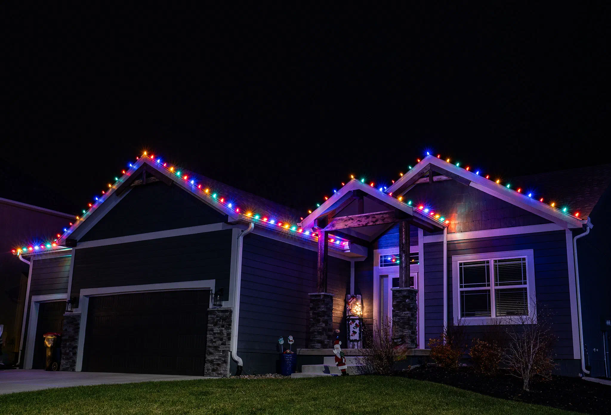 Single-story home with multicolor C9 holiday lights lining the rooflines at night